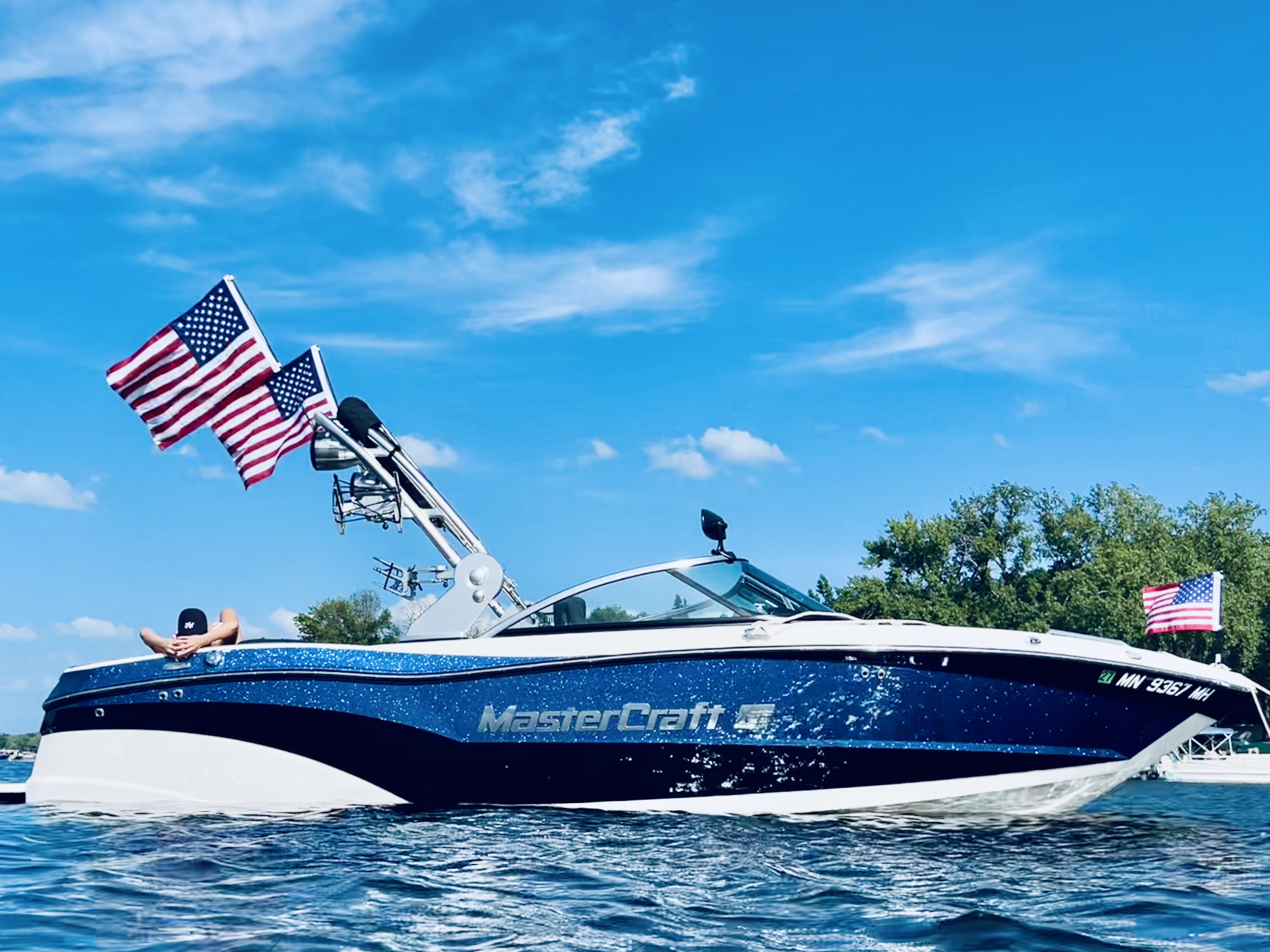 Blue MasterCraft boat with two flags flying from its tower